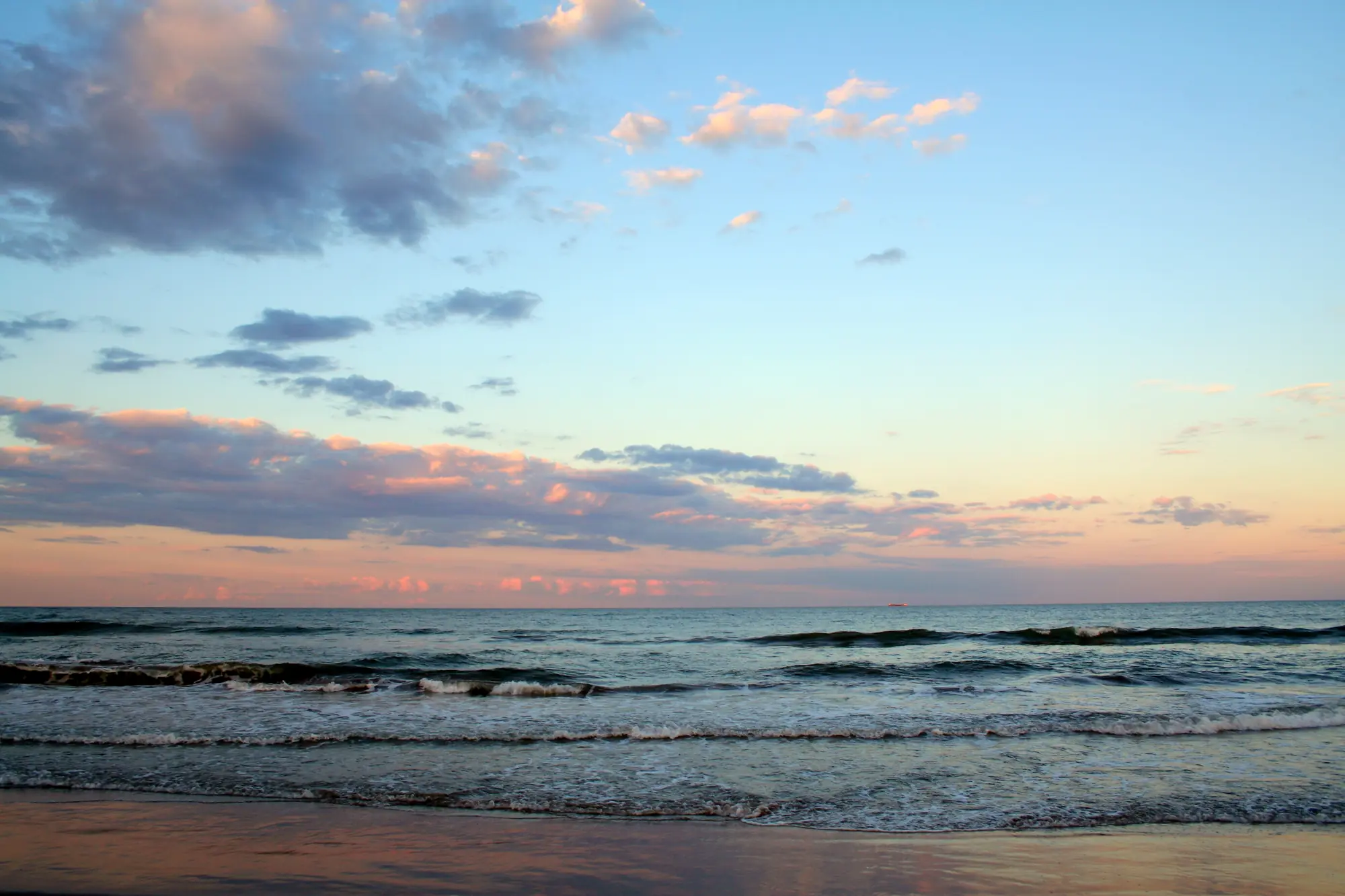 Waves on the beach at El Cabanyal in Valencia under a pink and grey sunset sky